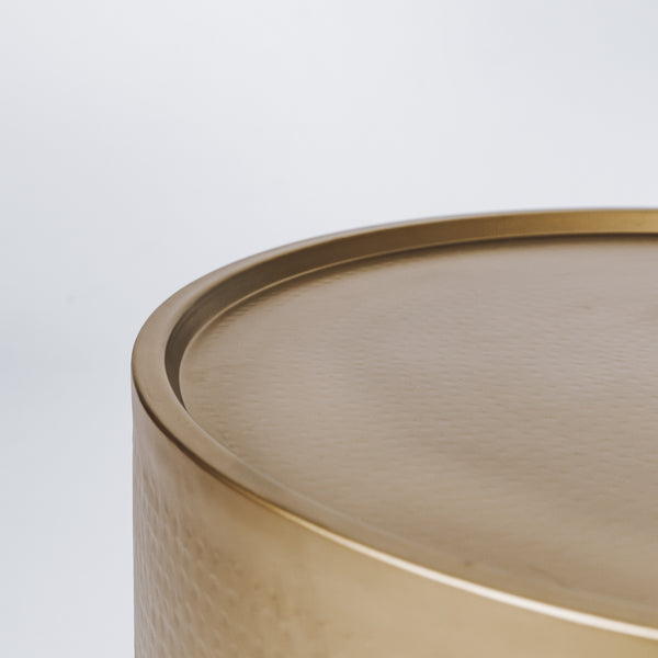An elegant hammered brass side table, reflecting warm ambient light
